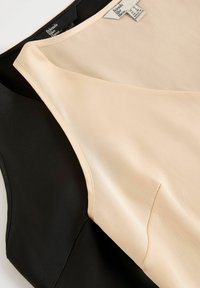 Top fără mâneci, de culoare neagră și bej, având o textură netedă, cu un design al gulerului în contrast și etichete ale brandului vizibile pe interior.