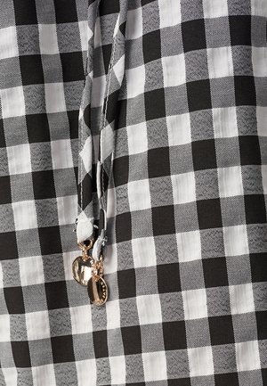 Schwarz-weißer karierten Stoff mit einem Zugband, das metallische silberne Akzente aufweist. Die Textur ist glatt und leicht.