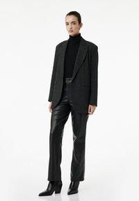 Gråternet oversized blazer med dobbelte knapper, sort ribbet turtleneck, sorte læderbukser og spidse block-heeled ankelstøvler.