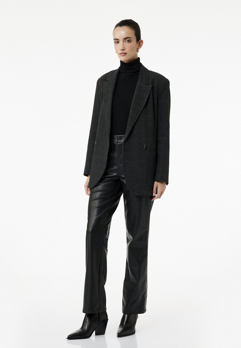 Gråternet oversized blazer med dobbelte knapper, sort ribbet turtleneck, sorte læderbukser og spidse block-heeled ankelstøvler.