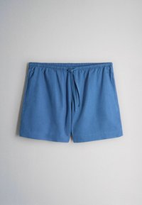 Pantaloni scurți cu talie elastică albastră, șnur frontal și buzunare laterale, așezați pe o suprafață plată pe un fundal gri deschis.