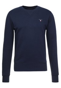 Mörkblå långärmad crewneck-tröja med ribbad mudd och nederkant, liten broderad GANT-logotyp på vänster bröst.