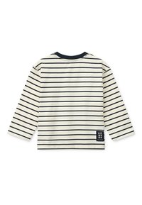 Kreemikas triiksärk pika varrukaga, millel on laigulised tumesinised horisontaalsed triibud. Omab ümara kaelusega ja all vasakul väikest musta silti. Pehme tekstuur.