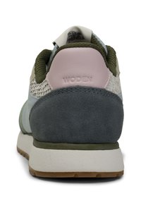 Sneaker mit grünem Wildleder-Heel, hellblauem Mesh-Obermaterial, neutralen Akzenten und Gummisohle. Merkmale das "WODEN"-Logo auf dem rosa Tab.