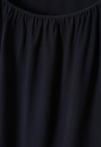 Tessuto blu navy con una morbida texture, caratterizzato da dettagli arricciati nella scollatura. Il materiale sembra leggero e liscio.