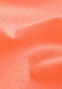 Korallikangas, jossa on sileä rakenne, hienovaraiset poimuviivat ja lempeät taitteet korostavat sen pehmeyttä ja tasaisuutta.