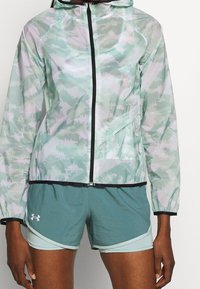 Chaqueta con capucha ligera en un patrón abstracto de verde menta y blanco, que presenta un cierre frontal, ribetes en negro contrastante y tejido transpirable.