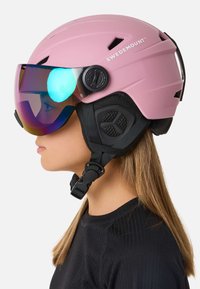 Roze skihelm met een glanzend vizier. Voorzien van ventilatiesleuven, verstelbare riemen en een getextureerd zwart accent aan de zijkant.