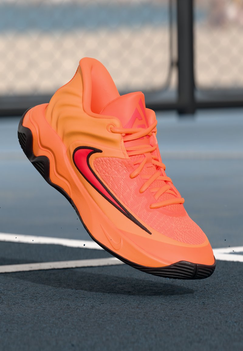Nike basketball shoe in bright orange with black accents. Textured upper, rounded shape, and prominent black swoosh logo on the side.