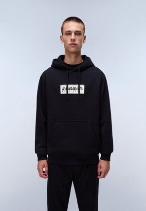 Black pullover hoodie in soft fabric features a front pocket and drawstring hood. White logo prominently displayed on the chest area.