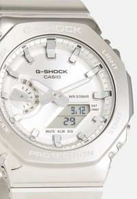 Montre G-SHOCK avec un boîtier en acier inoxydable argenté, affichage analogique-numérique, lunette texturée et grands marqueurs d'heure ; étanche jusqu'à 20 bars.