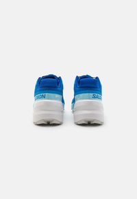 Chaussures de sport bleues avec tige en mesh, col rembourré et semelle intermédiaire blanche. Présente les marques "SALOMON" et "SPEEDCROSS" avec des accents bleu clair.