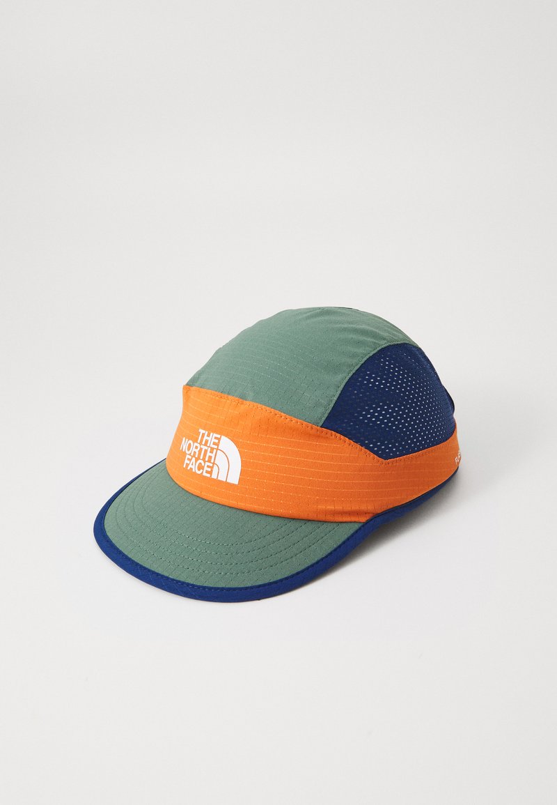 Barvita kapa s zelenimi, oranžnimi in modrimi paneli. Ima mrežasto obliko in širok rob. Bel logotip je natisnjen na sprednjem pasu. Lahka material.