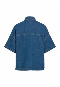 Vue arrière d'une chemise en denim bleu moyen à manches courtes, coupe large avec un détail de couture sur le haut du dos et les manches.