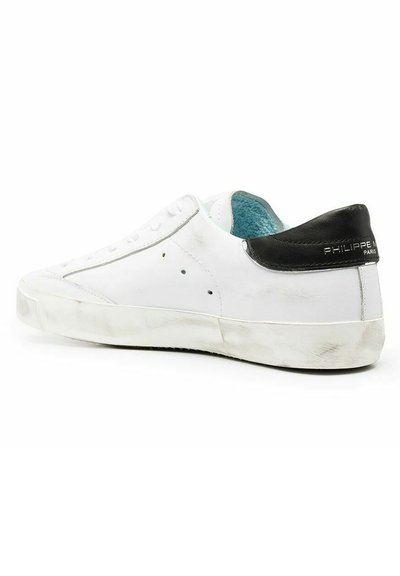 Sneaker bianco in pelle con accento nero sul tallone, superficie testurizzata, design con lacci e fodera turchese. Leggeri segni di usura visibili sulla suola.