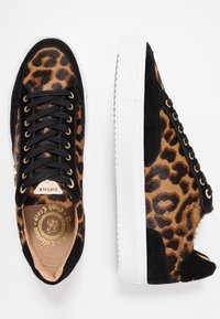 Baskets imprimées léopard noires et marron avec une finition texturée, des accents en daim noir, des œillets dorés et des semelles en caoutchouc blanches.