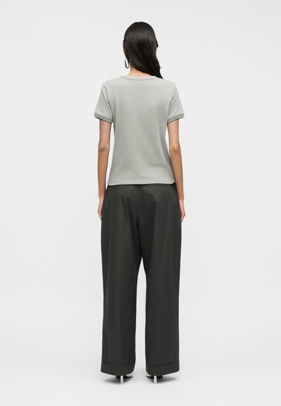 Ανοιχτό γκρι κοντομάνικο τοπ με γυρισμένα μανίκια σε συνδυασμό με άνετο, σκούρο γκρι παντελόνι με ίσια γραμμή και γυρισμένο τελείωμα.