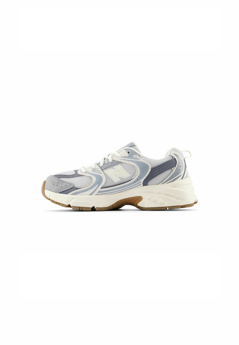 Scarpa sportiva grigio chiaro con tomaia in rete, dettagli sintetici, suola intermedia bianca e suola in gomma. Presenta una punta rotonda e un sistema di allacciatura.