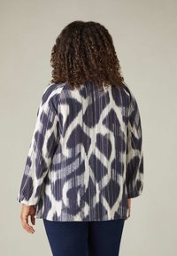 Blusa a maniche lunghe realizzata in tessuto leggero, caratterizzata da un motivo astratto blu navy e bianco con righe verticali e una vestibilità rilassata.