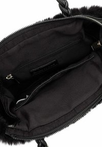 Interno della borsa in pelliccia sintetica nera con fodera in tessuto liscio, dotata di una tasca con cerniera e due scomparti aperti. Chiusura con cerniera e manici intrecciati.