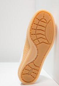 Podeszwa beżowego trampka z teksturowanym wzorem bieżnika, rozmiar 37, z brandingiem "G-STAR RAW" na części piętowej.