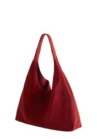 Red suede hobo bag with a single, wide shoulder strap and an open top. Features a smooth texture and an exterior slip pocket.
