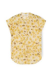 Kortebloeve blouse van lichtgele stof met een bloempatroon in donkergeel en bruin. Heeft een knoopsluiting aan de voorkant en een ronde zoom.