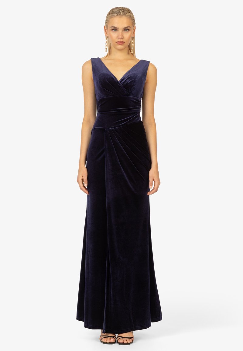 Dunkelblaues Samtkleid mit V-Ausschnitt, ärmellosem Design und gefalteten Details an der Taille, das bis zu einem bodenlangen Saum reicht.