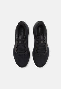 Paire de chaussures de course noires Nike avec lacets, vue de dessus sur un fond gris clair.