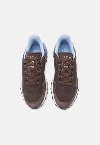 Καφέ αθλητικά παπούτσια με επάνω μέρος από σουέντ και δίχτυ, ανοιχτό μπλε λεπτομέρειες, καφέ κορδόνια, υφή σόλας και εκτυπωμένη λεπτομέρεια λογότυπου στη γλώσσα.
