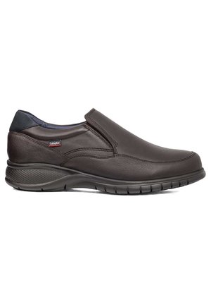 Zapato marrón de cuero sin cordones con un diseño elegante, punta redondeada, suela texturizada y gomas elásticas para un fácil uso. Presenta un sutil logo de la marca.