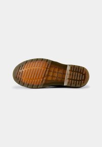 Sola de sapato em borracha preta com um padrão texturizado. A sola é laranja semi-transparente com sulcos para tração e aderência.