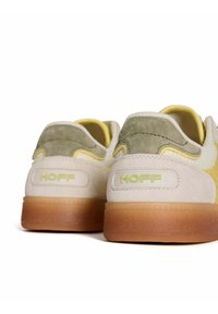 Zapatillas con parte superior de ante beige y malla amarilla, acentos en verde oliva y suela de goma transparente; logo "HOFF" destacado en el talón.