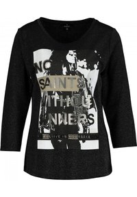 Schwarzes Langarm-T-Shirt mit V-Ausschnitt, das mit einem metallischen Grafikdruck und Text versehen ist. Das Design enthält ein Bild einer Figur und einen Slogan.