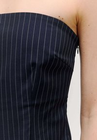 Halsloses navy-blaues Kleid mit vertikalen weißen Streifen, strukturiertem Oberteil und verdecktem seitlichem Reißverschluss, aus glattem Stoff gefertigt.