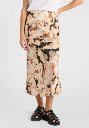 Jupe midi tie-dye dans des teintes pêche, noire et crème ; tissu léger ; ourlet évasé ; associée à des sandales noires à brides.