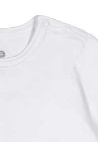 Hvid bomulds T-shirt med rund halsudskæring, der har to trykknapper på skulderen og fine ribbede sømme langs kraven.