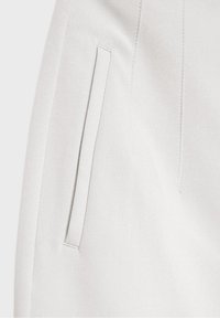 Light gray tailored trousers, smooth fabric, side pocket detail, structured design, clean lines, and subtle stitching accents.