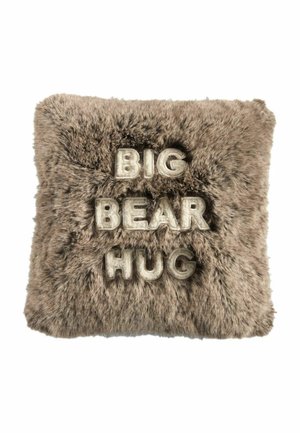 Neliömäinen harmaa tekoturkistyynynpäällinen, jossa koholla olevat valkoiset kirjaimet muodostavat tekstin "BIG BEAR HUG" kolmessa rivissä.