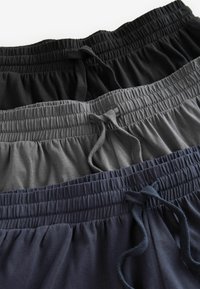 Trei perechi de pantaloni cu talie elastică, în culorile negru, gri și bleumarin. Fiecare pereche are șnururi de ajustare și un material moale, texturat.
