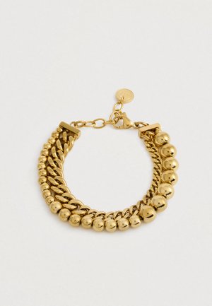 Guldtonet armbånd med to sammenkædede kæder, hvoraf den ene har runde perler, samt en krabbe-lås med en justerbar kæde og et lille rundt mærke.