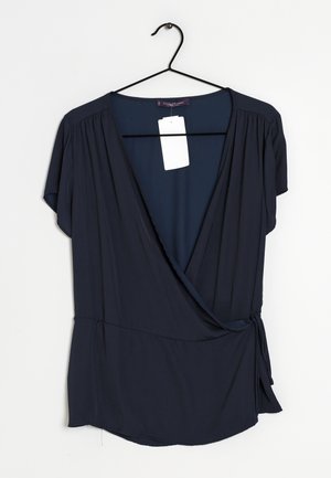 Blusa avvolgente blu navy a maniche corte, con una profonda scollatura a V, dettagli arricciati sulle spalle e un nastro di legatura laterale.