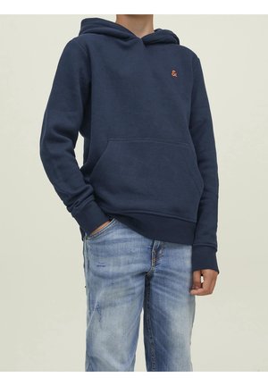 Hoodie marine en mélange de coton avec poche frontale, poignets et bas côtelés. Petit logo orange sur la poitrine. Porté avec un jean bleu clair.
