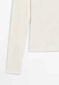 Langärmeliges, cremefarbenes Hemd mit unifarbenem Stoff und schlichter Saumverzierung.