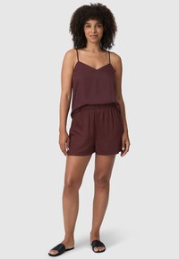 Top senza maniche bordeaux con scollo a V e spalline regolabili abbinato a pantaloni corti elasticizzati in vita. Tessuto morbido e vestibilità comoda.