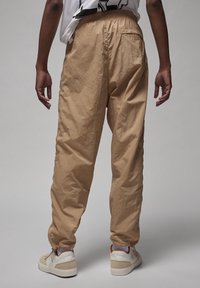 Beige, lätta tapered byxor med texturerad yta, elastisk midja och sidofickor. Parat med vita sneakers.