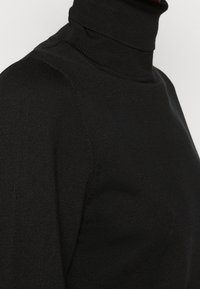 Schwarzer Rollkragenpullover mit einem taillierten Design, weichem Material und gerippten Akzenten am Kragen und an den Schultern.