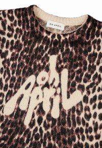 Brūnas un krēmkrāsas leoparda raksts adīta džemperis ar lielu "April" logotipu baltā krāsā. Uz birkas rakstīts "OH APRIL." Mīksta tekstūra, apaļas kakla dizains.