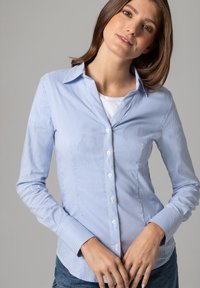 Light blue striped button-up shirt with long sleeves, a classic collar, and white buttons, featuring a fitted silhouette and smooth texture.