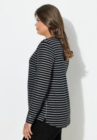 Schwarz- und grau gestreiftes Langarmshirt mit bequemer Passform, seitlichen Schlitzen und glatter Textur. Mit einem einfachen Logo auf dem Ärmel akzentuiert.